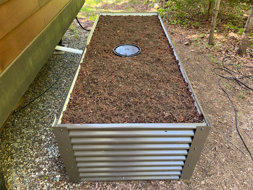Raised greywater mulch basin next to tiny house