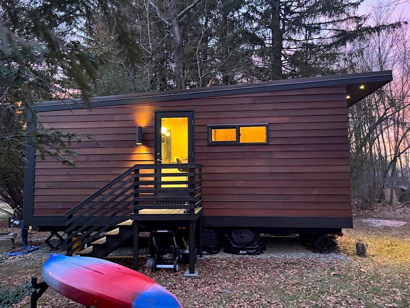 Modern cedar-clad tiny house on wheels at dusk